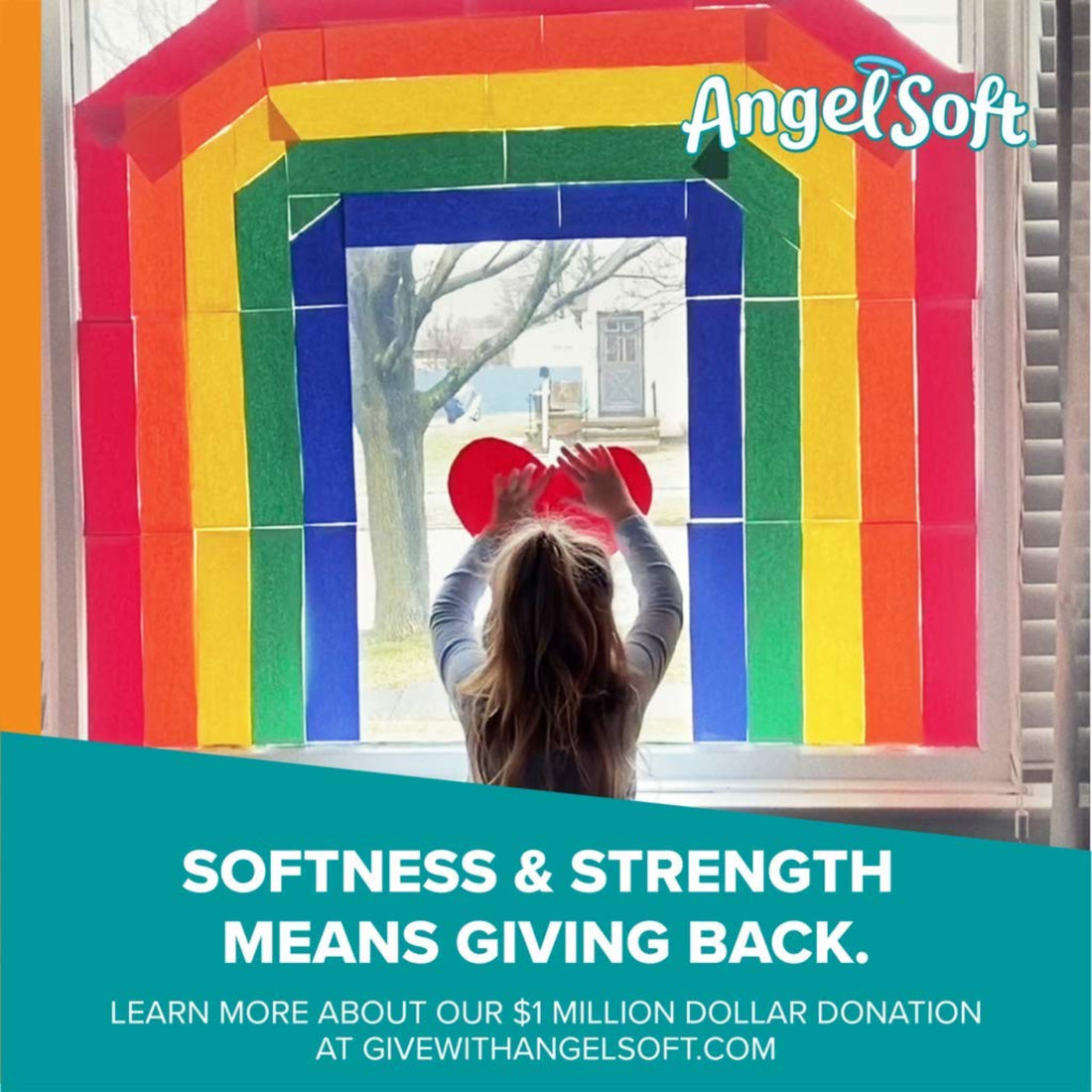 Person holding a heart-shaped object in front of a colorful window display with 'Angel Soft' branding.