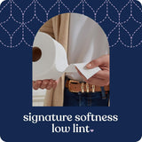 Person holding toilet paper with text 'signature softness low lint' on a blue background