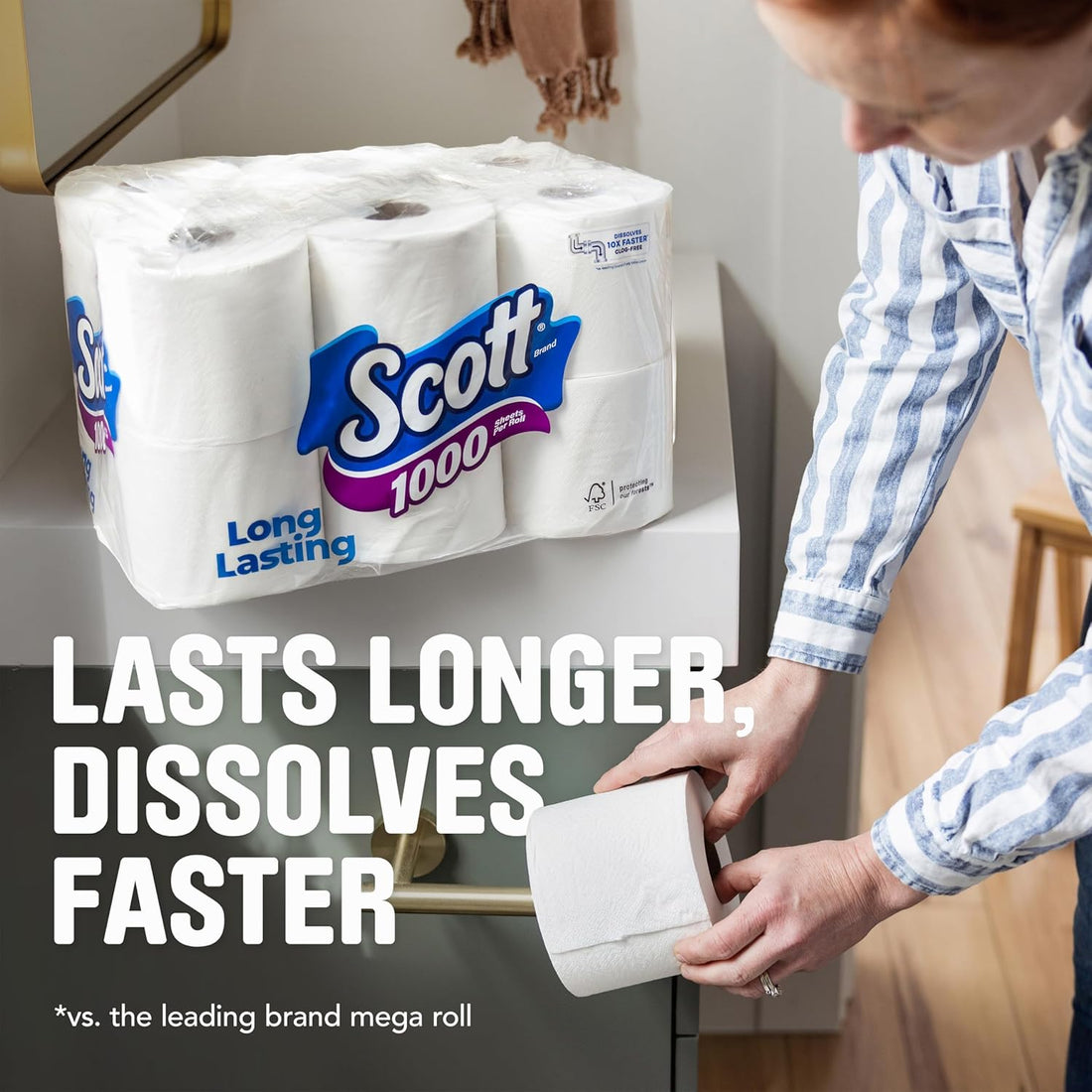 Person holding a Scott toilet paper roll with packaging in the background, emphasizing product features.