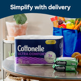 Cottonelle Ultra Comfort toilet paper and wipes on a table with groceries in the background.