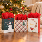 Hallmark Christmas gift bags (Santa, Snowman, Plaid) with red tissue by the tree